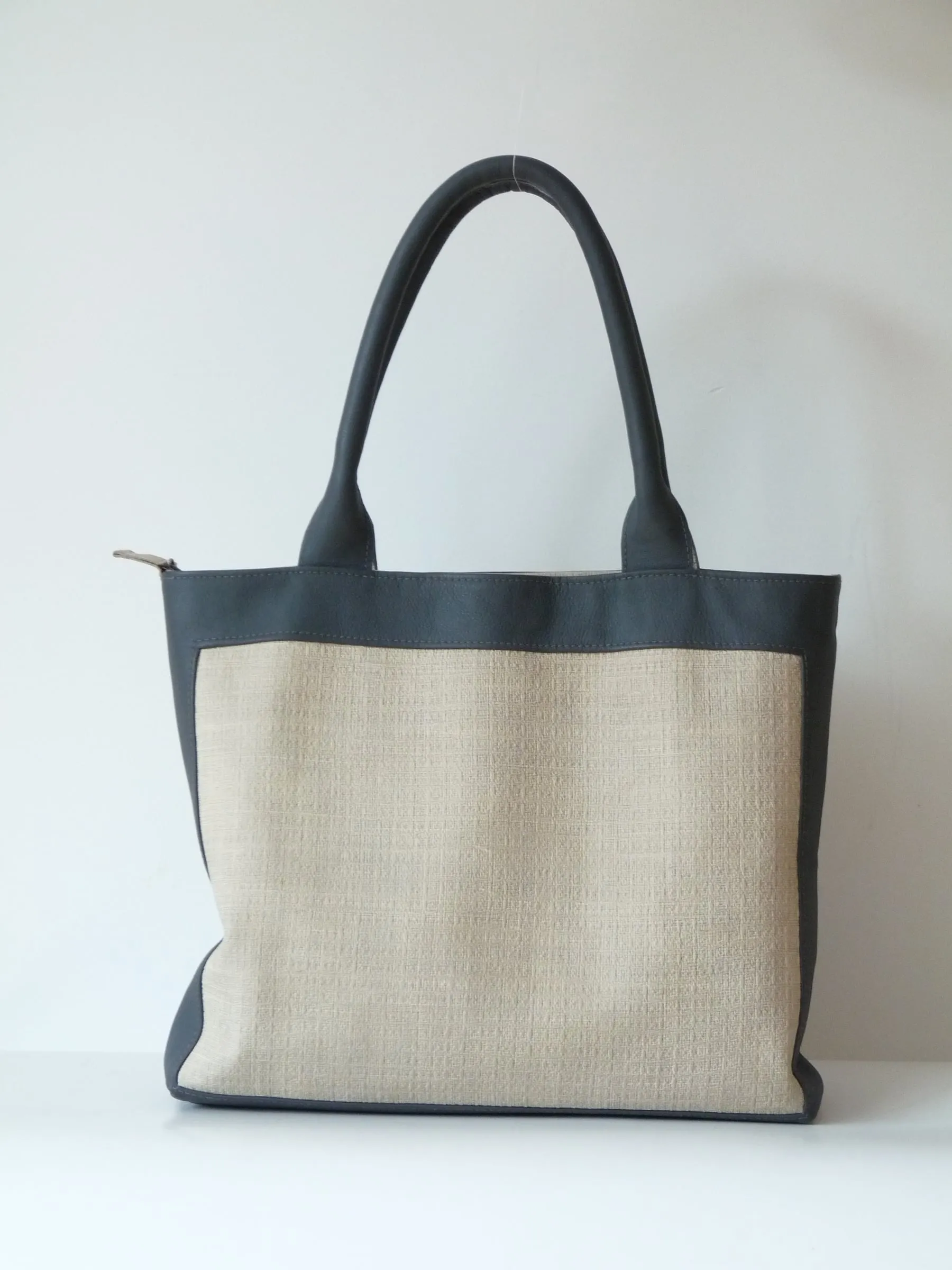 Shopper van beige stof met donkere leren randen en hengsels